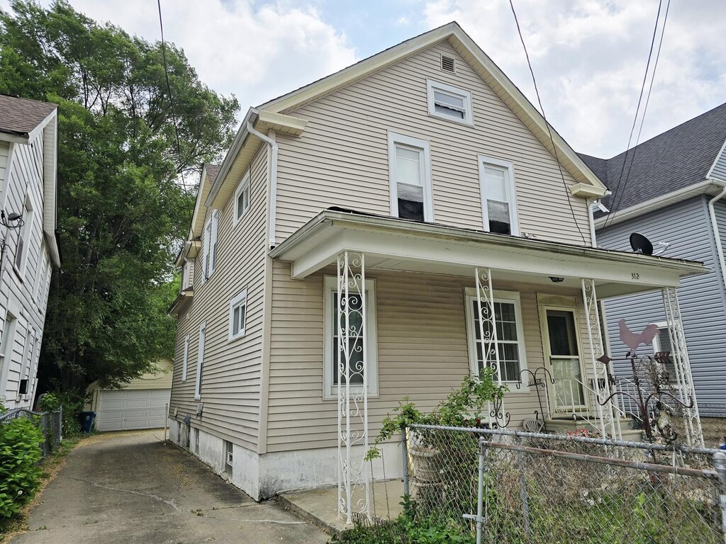 view of front of house featuring an outdoor structure, covered porch, fence, and a detached garage