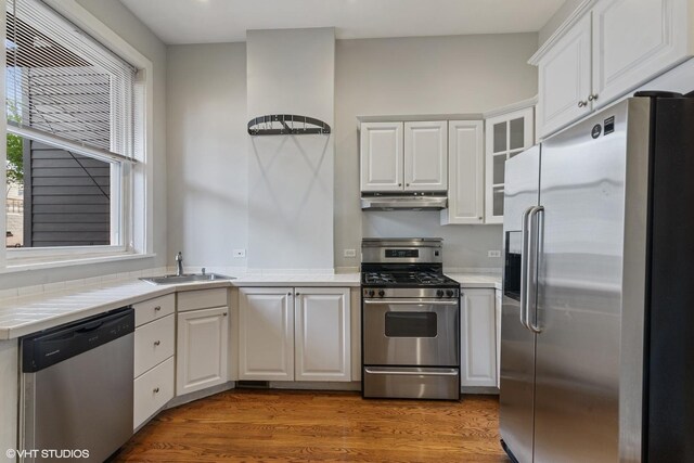 2232 W Homer St, Chicago, IL 60647 - kitchen featuring appliances with stainless steel finishes, under cabinet range hood, white cabinets, and tile countertops