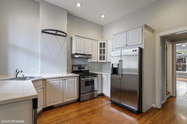 2232 W Homer St, Chicago, IL 60647 - kitchen with stainless steel appliances, a sink, wood finished floors, tile counters, and under cabinet range hood