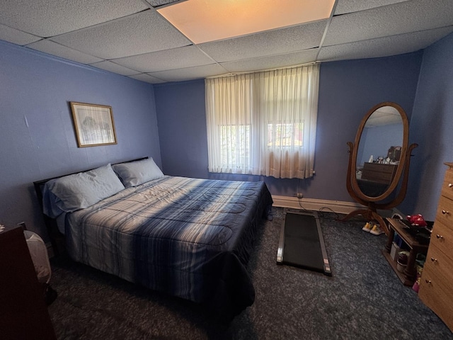 bedroom with carpet, a paneled ceiling, and baseboards