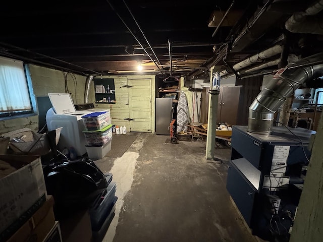 below grade area featuring freestanding refrigerator and washing machine and clothes dryer