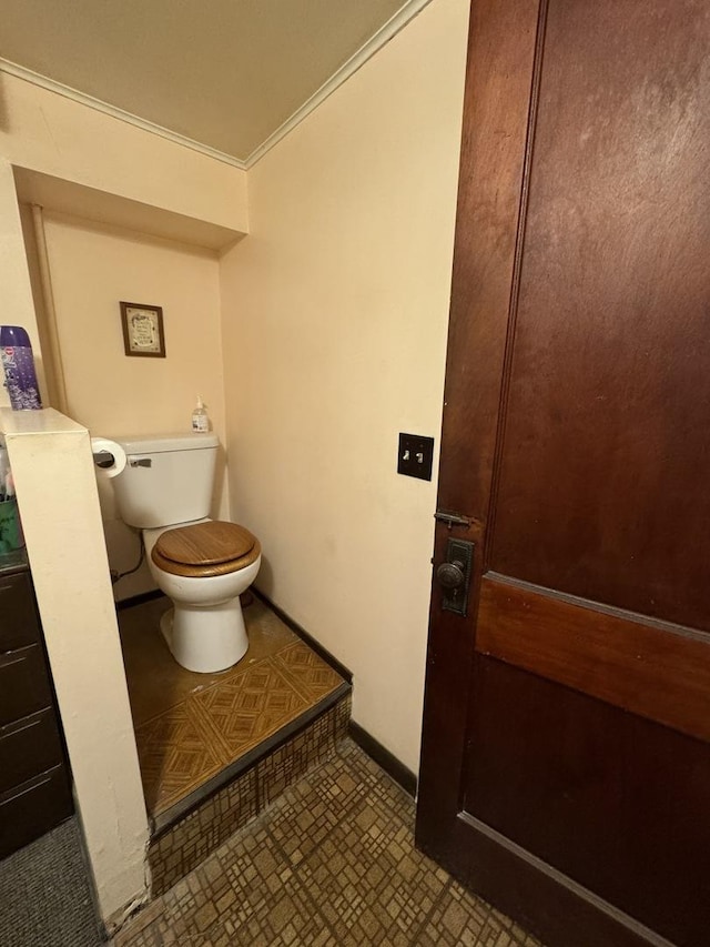 bathroom with toilet, ornamental molding, baseboards, and tile patterned floors
