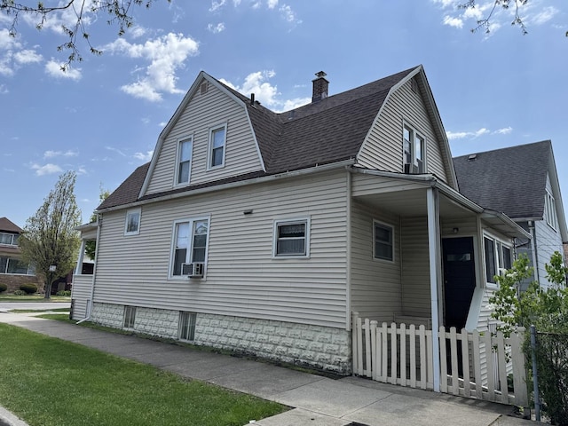 view of home's exterior with a gambrel roof, a shingled roof, fence, and a chimney