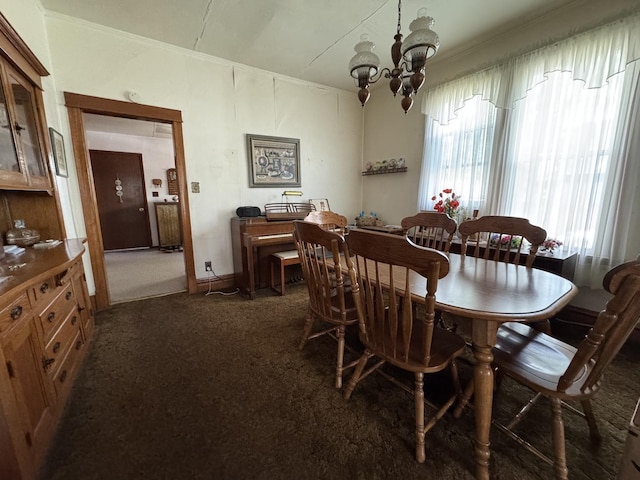 dining space featuring a chandelier, dark colored carpet, and crown molding