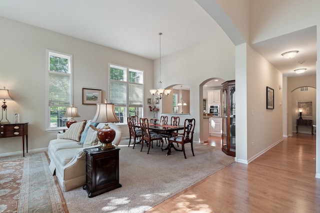 2904 Portage St, Naperville, IL 60564 - living area with arched walkways, light wood-style floors, a chandelier, baseboards, and a towering ceiling