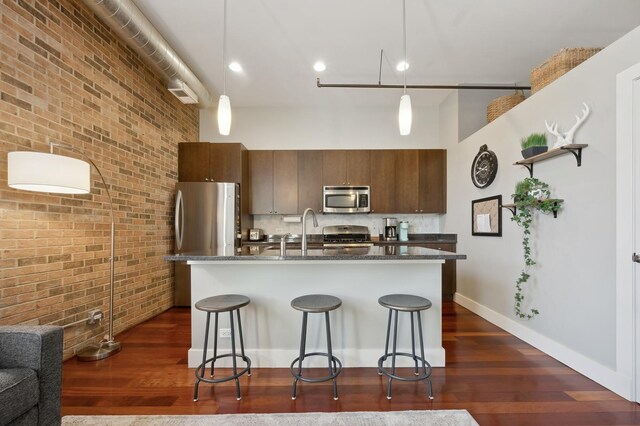 3133 N Lakewood Ave Unit 3I, Chicago, IL 60657 - kitchen with stainless steel appliances, brick wall, a breakfast bar, a high ceiling, and dark wood finished floors