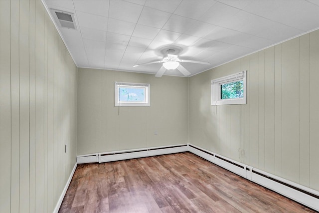 spare room featuring wood finished floors, wooden walls, ceiling fan, and baseboards