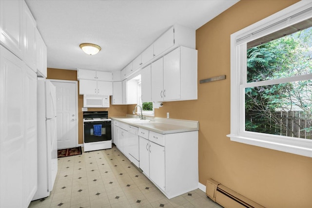 kitchen featuring white appliances, a sink, baseboard heating, and plenty of natural light