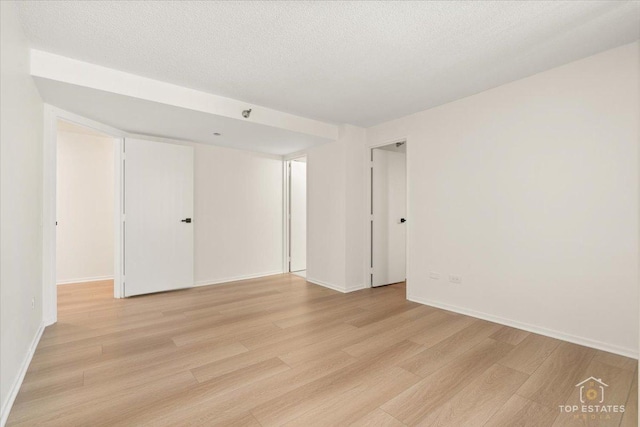 unfurnished bedroom with light wood finished floors, baseboards, and a textured ceiling