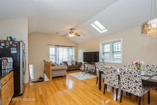 dining room featuring light wood finished floors, vaulted ceiling, ceiling fan, and a skylight