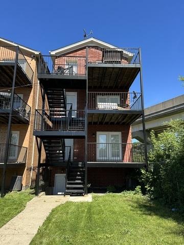rear view of house with a balcony and a yard