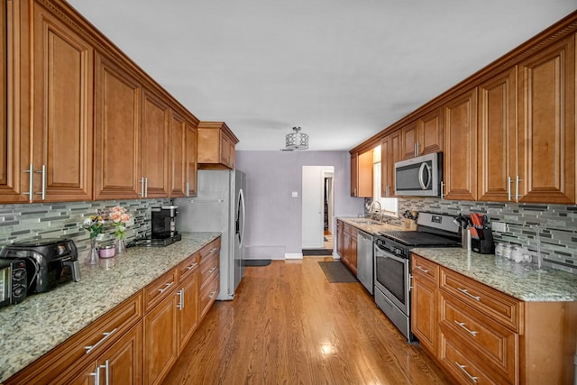 1636 S 14th Ave, Maywood, IL 60153 - kitchen featuring appliances with stainless steel finishes, brown cabinetry, baseboards, backsplash, and wood finished floors