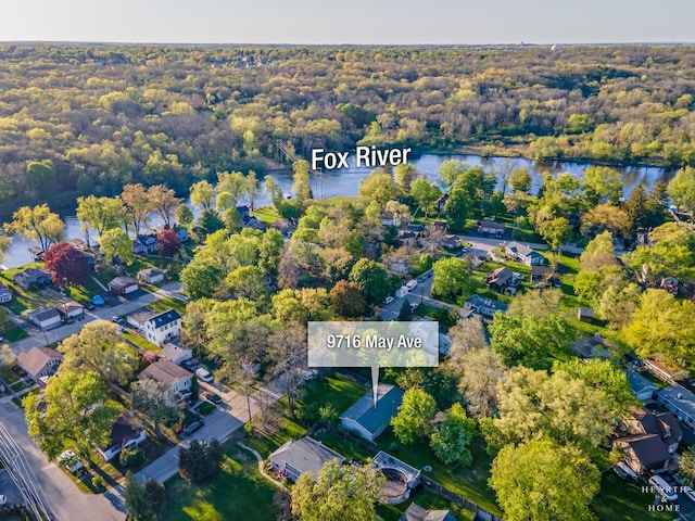 view of property location with a nearby body of water and a forest