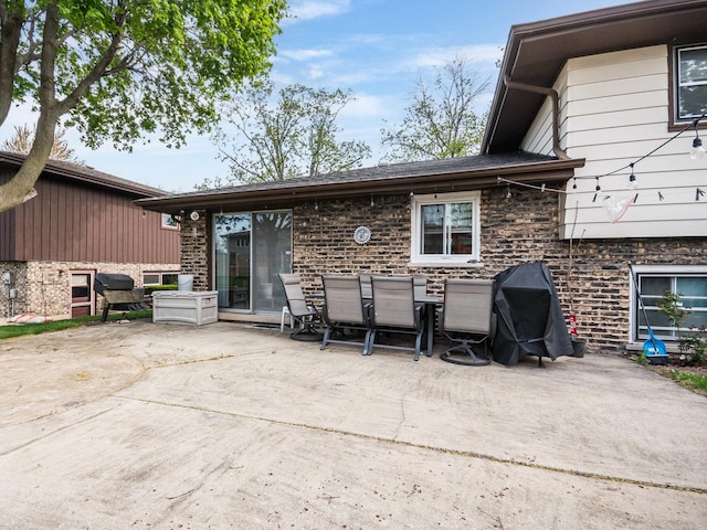 back of property featuring a patio, stone siding, and outdoor dining space
