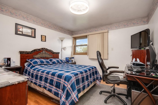 bedroom with wood finished floors and an office area