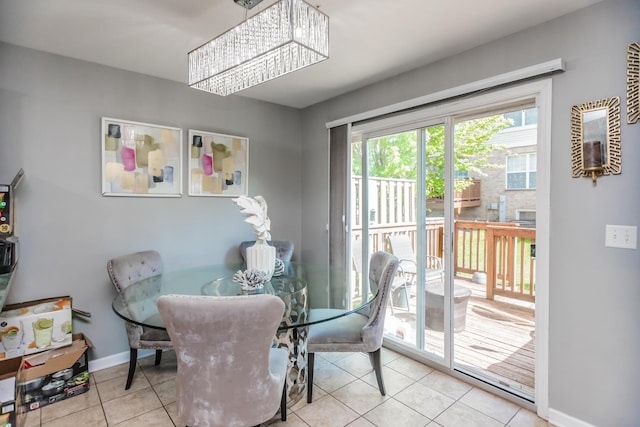 dining area with a chandelier, tile patterned floors, and baseboards