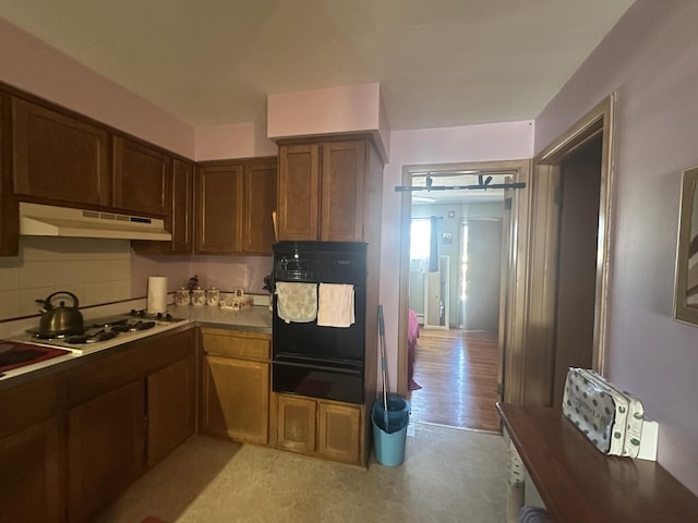 16 King Arthur Ct Unit 16, Northlake, IL 60164 - kitchen with a warming drawer, black oven, under cabinet range hood, white gas cooktop, and decorative backsplash