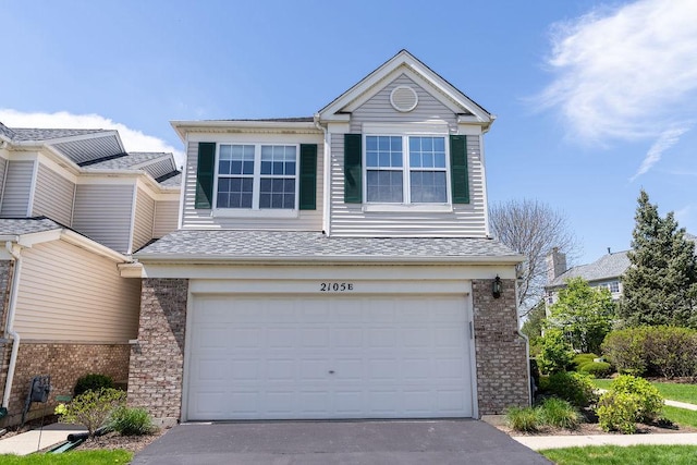 view of front facade featuring a garage, brick siding, driveway, and a shingled roof