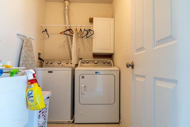clothes washing area featuring washing machine and dryer and cabinet space