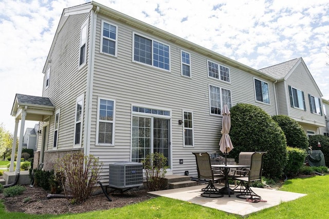 rear view of property featuring cooling unit, a patio area, and a yard