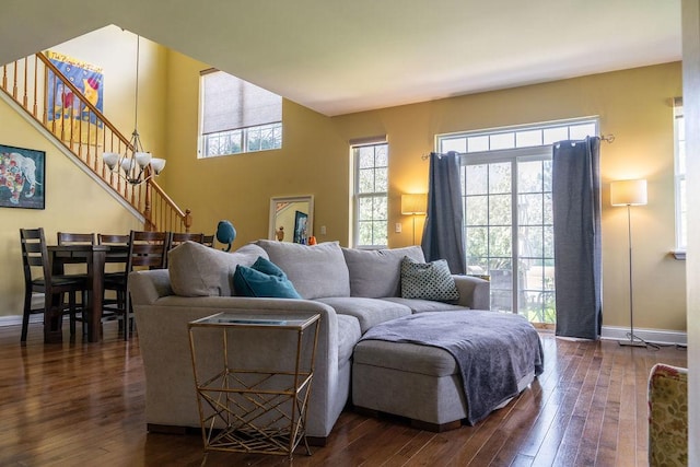 living area with dark wood-style flooring, baseboards, and stairs