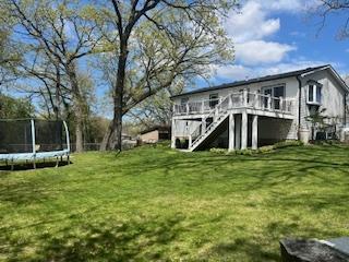 1811 Maplewood Ct, Lindenhurst, IL 60046 - back of property with a trampoline, a deck, stairway, and a lawn
