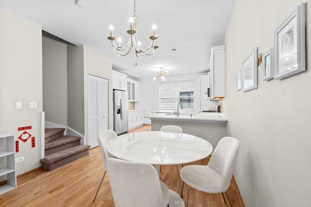 dining area with a chandelier, stairway, light wood finished floors, and baseboards