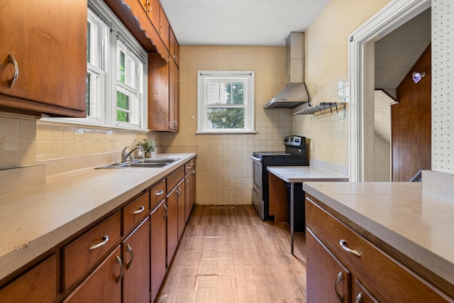 711 W Iowa St, Urbana, IL 61801 - kitchen featuring electric range, a sink, wall chimney exhaust hood, light wood-type flooring, and brown cabinets