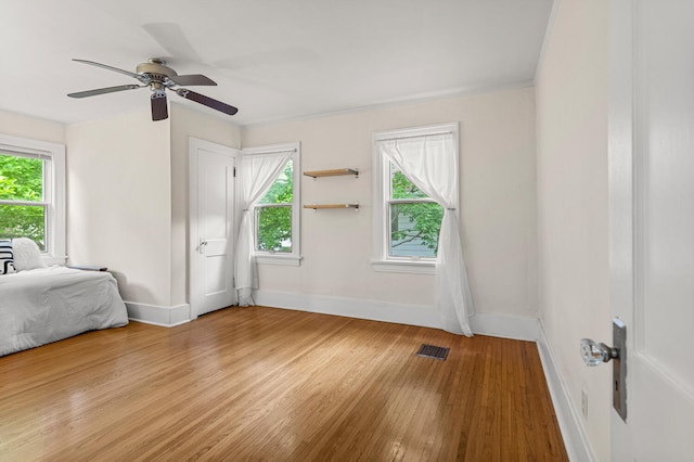 711 W Iowa St, Urbana, IL 61801 - unfurnished bedroom with light wood-style flooring, multiple windows, baseboards, and a ceiling fan