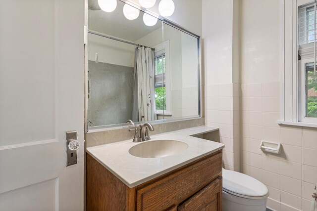 711 W Iowa St, Urbana, IL 61801 - full bathroom with vanity, toilet, plenty of natural light, tile walls, and curtained shower