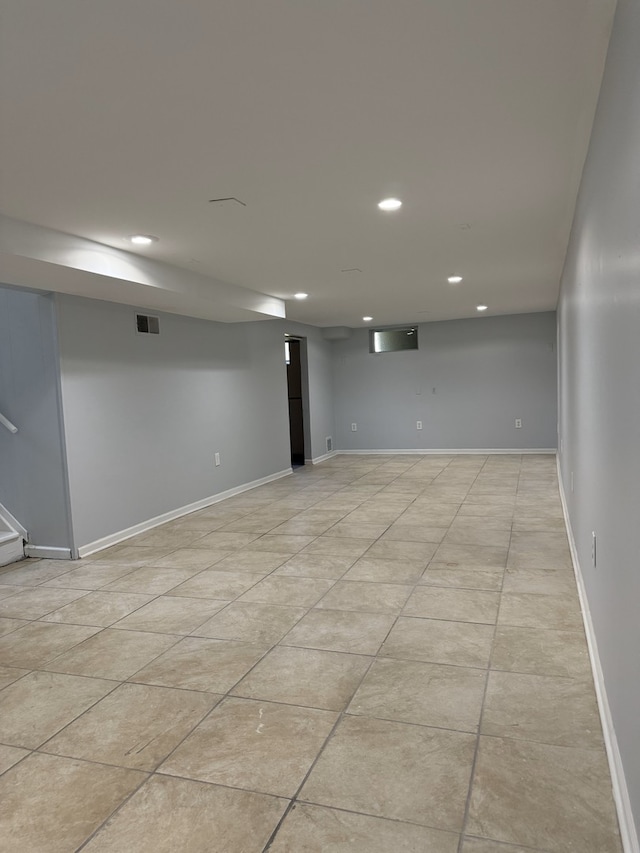 finished below grade area featuring recessed lighting, baseboards, stairs, and light tile patterned floors