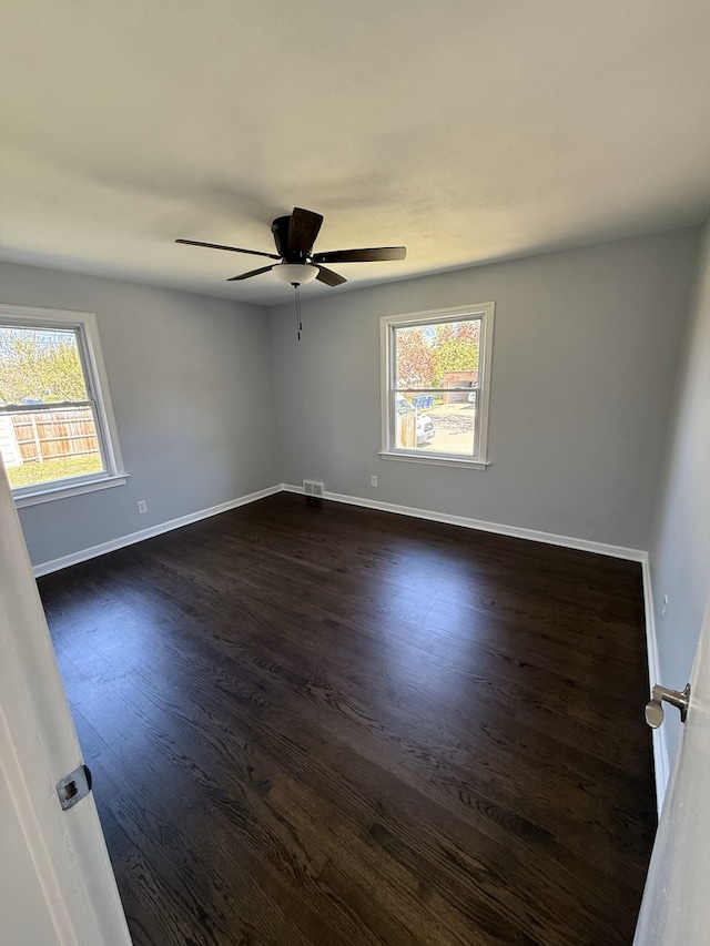 spare room with plenty of natural light, dark wood-style floors, baseboards, and ceiling fan