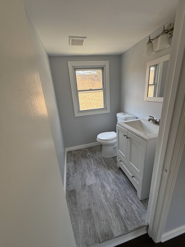 bathroom featuring wood finished floors, toilet, baseboards, and vanity
