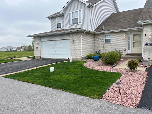view of front facade featuring asphalt driveway, a front yard, brick siding, and a garage