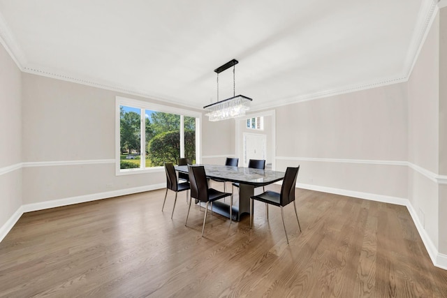 dining space with baseboards, a chandelier, wood finished floors, and crown molding