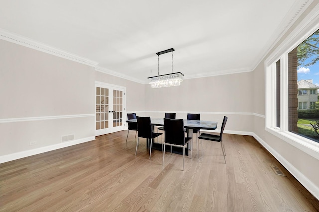 dining space with french doors, wood finished floors, baseboards, crown molding, and a chandelier