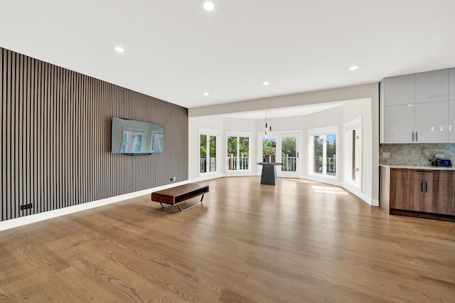 unfurnished living room with wood finished floors, recessed lighting, and baseboards