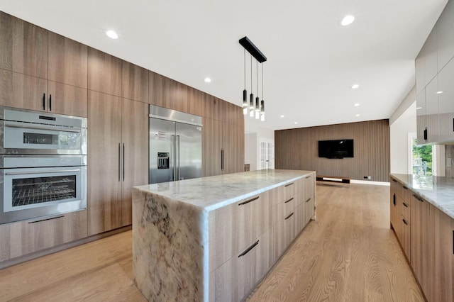 kitchen featuring modern cabinets, stainless steel appliances, light stone countertops, light wood finished floors, and recessed lighting