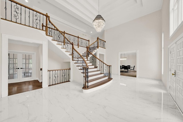 entrance foyer featuring a high ceiling, marble tiled floors, stairs, a chandelier, and french doors