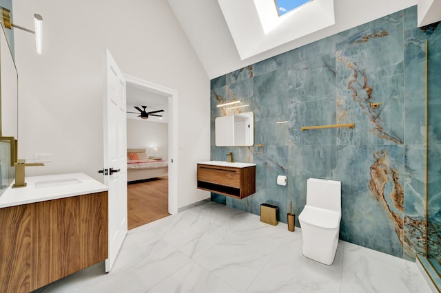 bathroom with a skylight, vaulted ceiling, ensuite bathroom, tile walls, and vanity