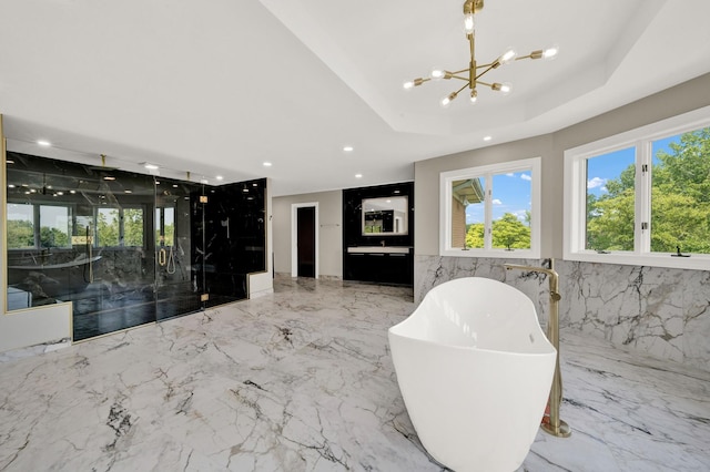 bathroom featuring a chandelier, a freestanding bath, a tray ceiling, recessed lighting, and a marble finish shower