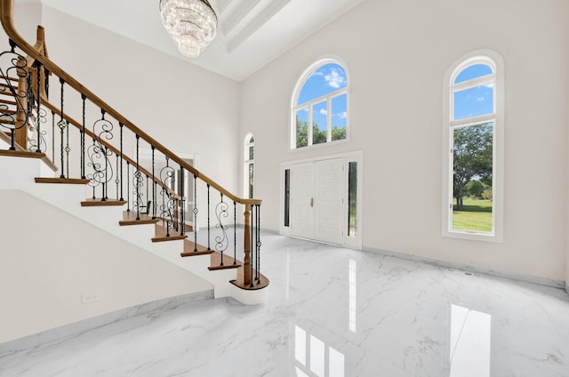 entrance foyer featuring marble tiled floors, a high ceiling, a chandelier, stairs, and baseboards