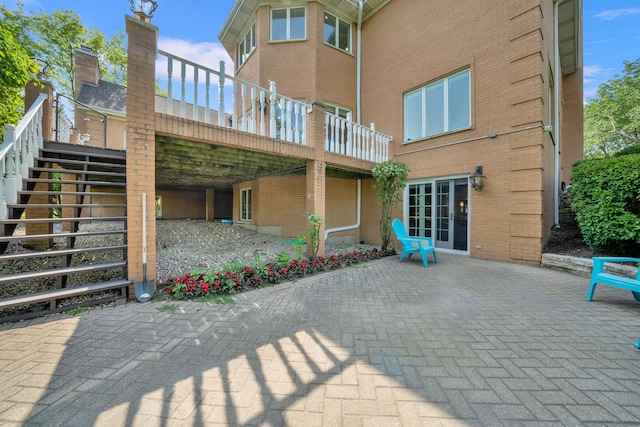 rear view of property with stairs, a patio, and brick siding