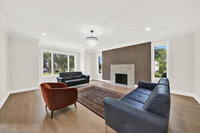 living area featuring baseboards, plenty of natural light, a chandelier, wood finished floors, and ornamental molding