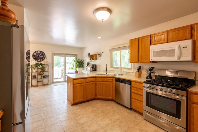 7038 Bentley Dr, Gurnee, IL 60031 - kitchen with stainless steel appliances, a sink, a peninsula, light countertops, and brown cabinetry