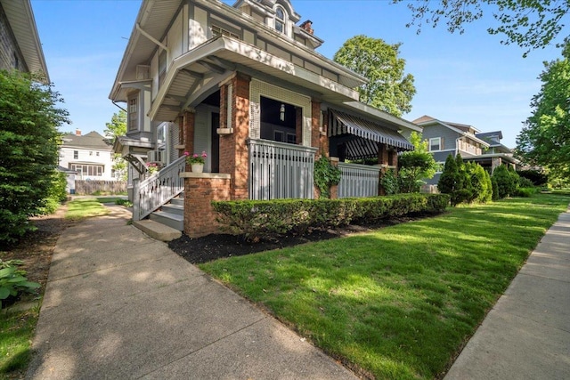 view of front facade featuring a front yard, brick siding, and a porch