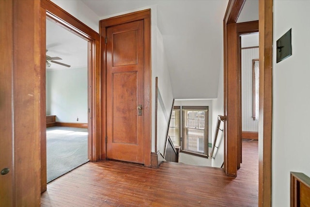 hall featuring an upstairs landing, wood finished floors, and baseboards