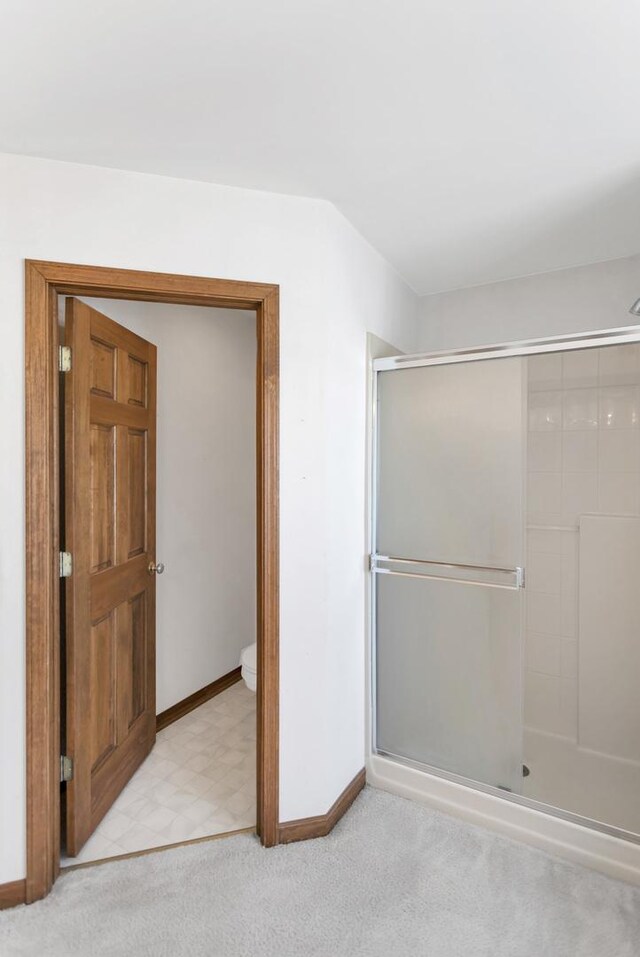 full bathroom featuring a stall shower, baseboards, toilet, and carpet flooring