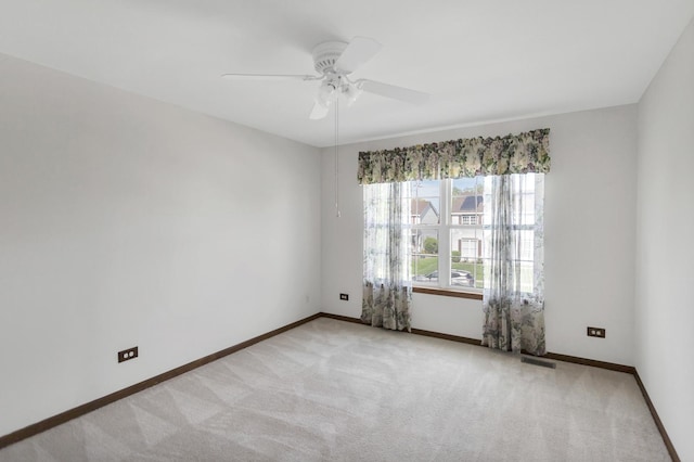 unfurnished room featuring light colored carpet, ceiling fan, and baseboards