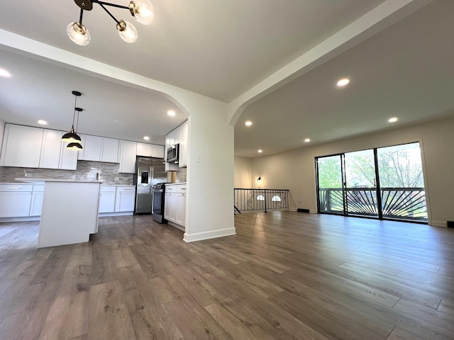 kitchen featuring open floor plan, stainless steel appliances, backsplash, dark wood-style flooring, and recessed lighting